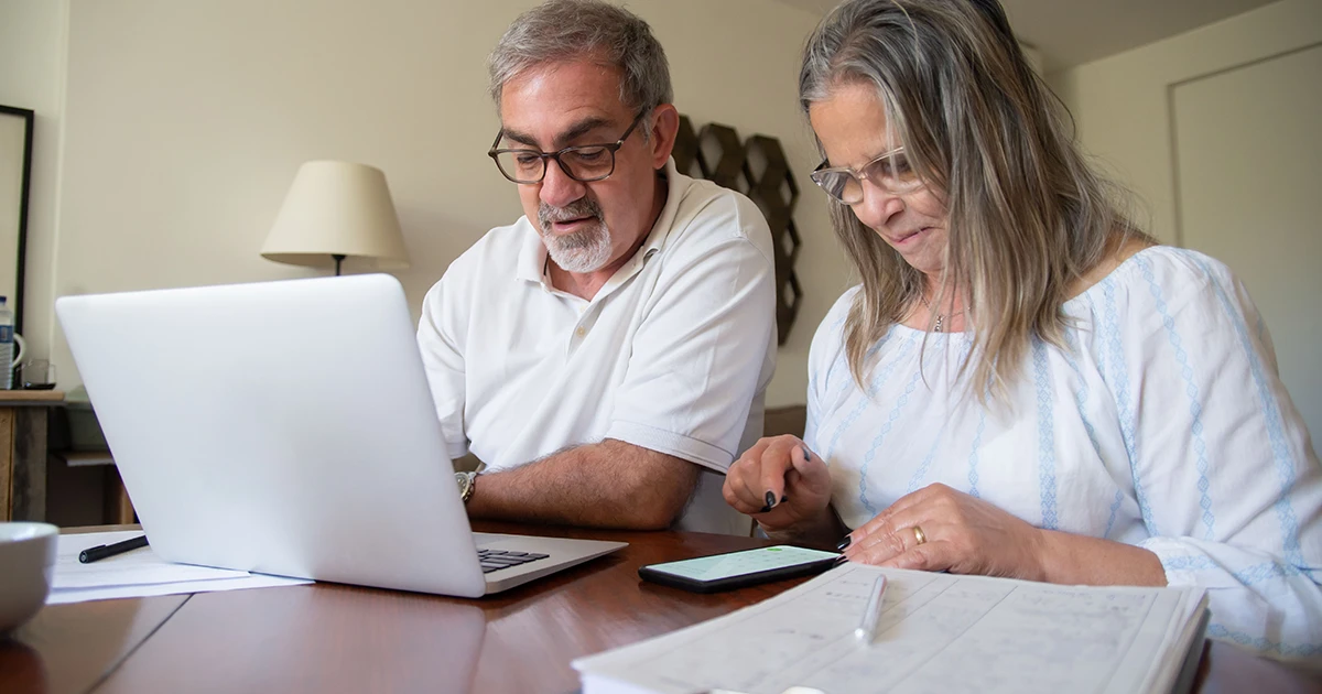 Couple sitting at a table reviewing a retirement plan document with a financial advisor